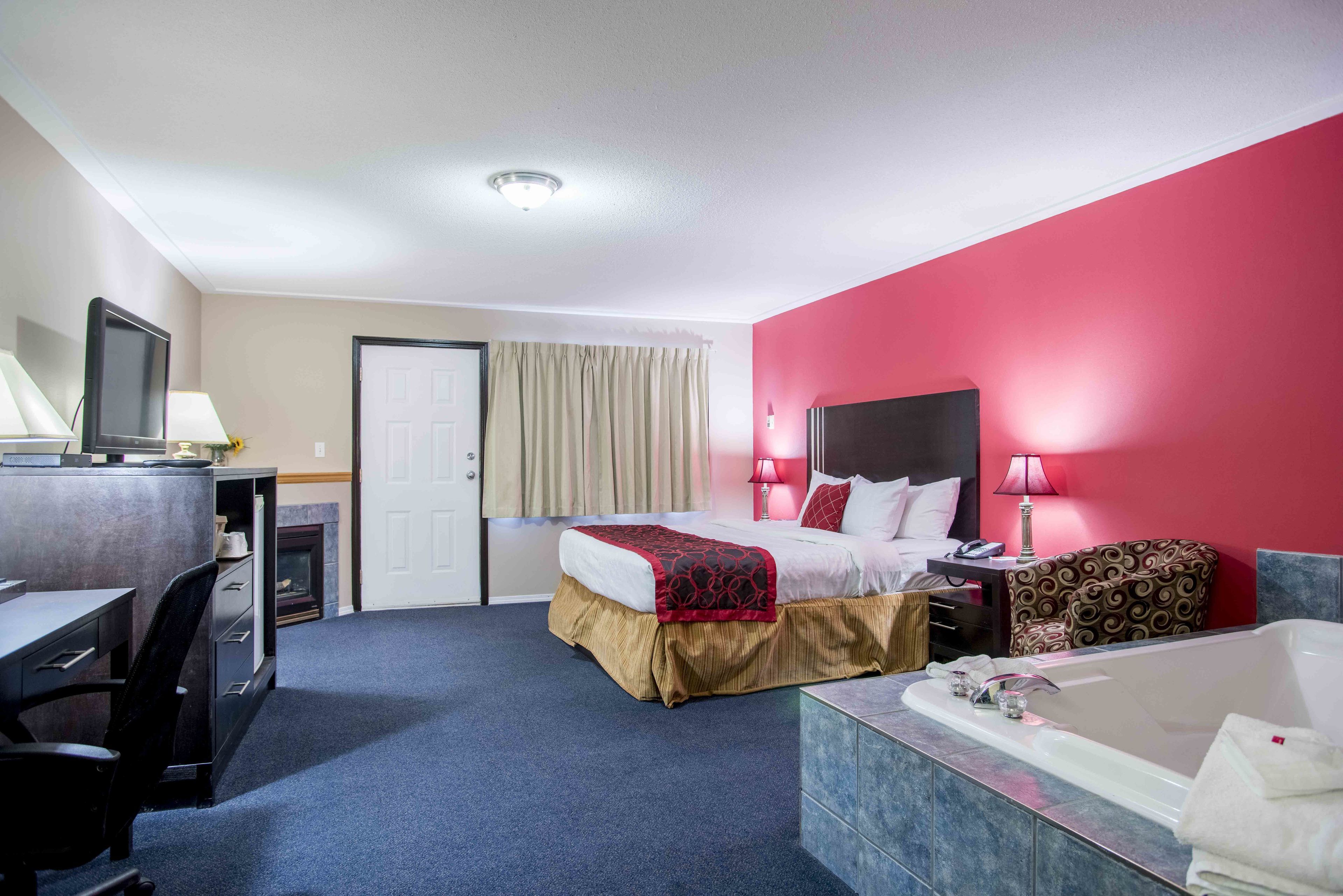 Una habitación de hotel con cama, escritorio, silla y baño con bañera.