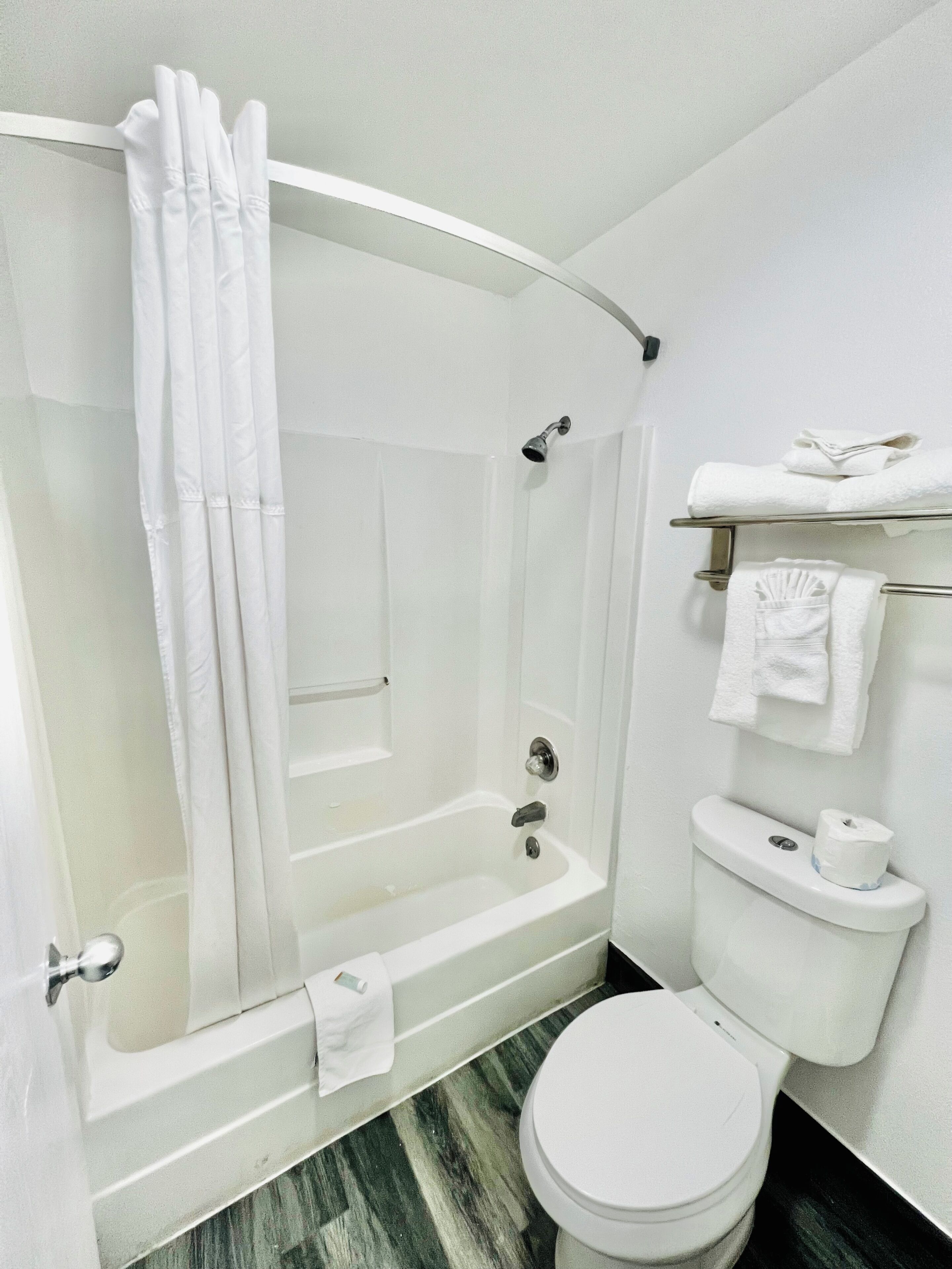 A bathroom with a bathtub, toilet, and a shower curtain.