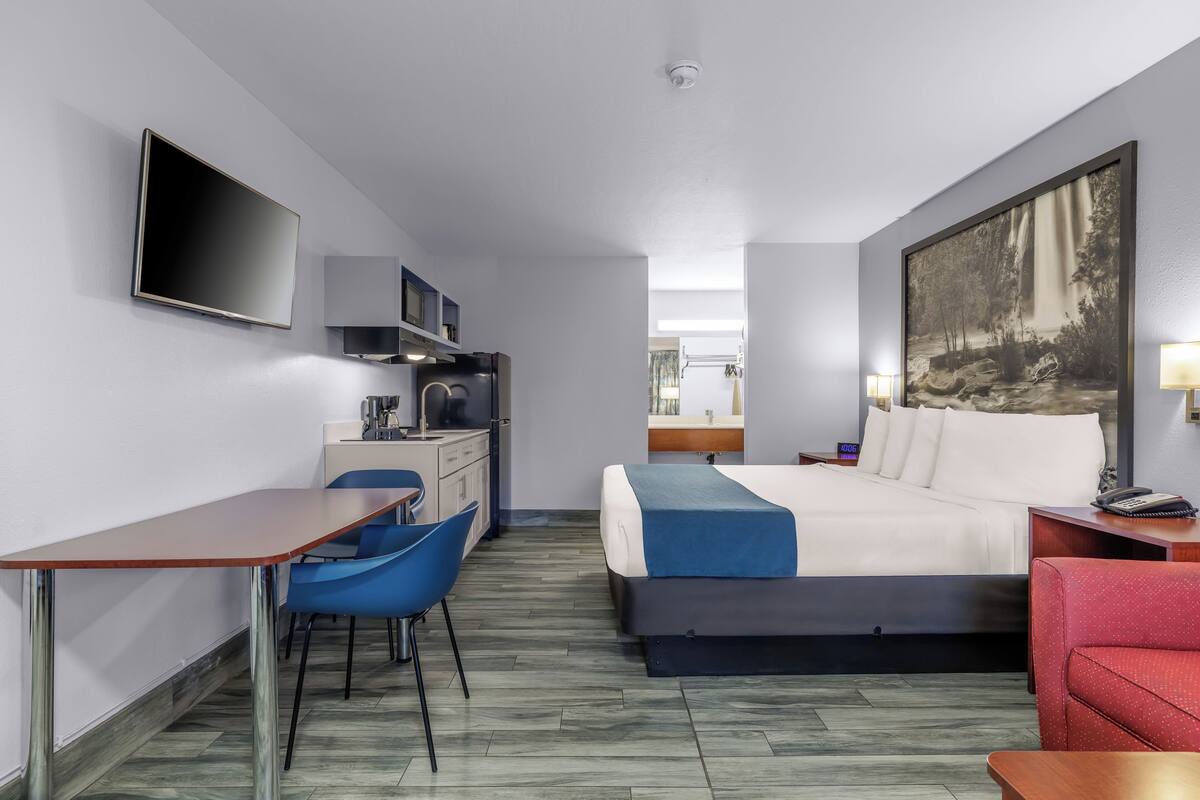A compact hotel room with a bed, desk, chair, and a TV.