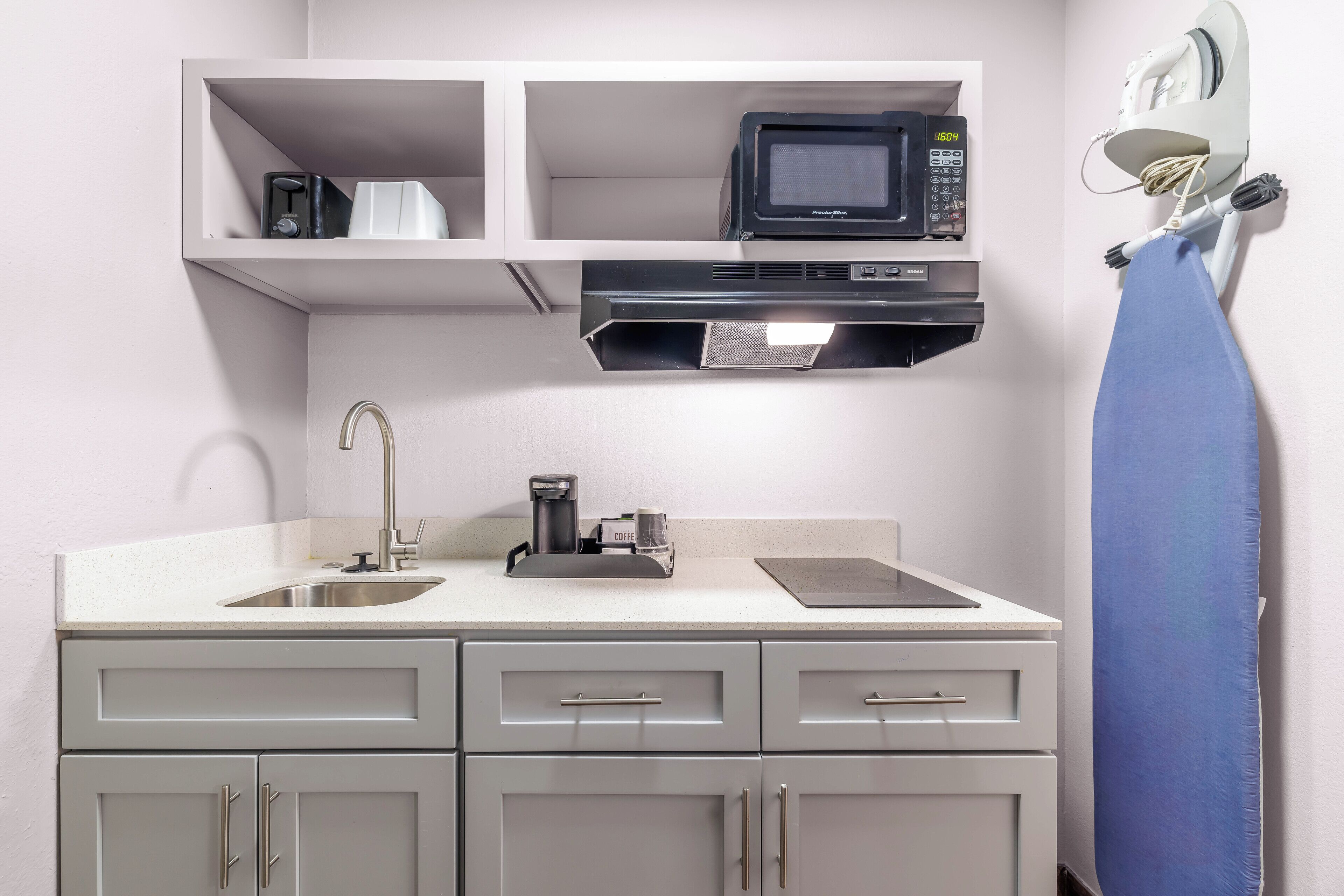 A kitchenette with a microwave, coffee maker, and sink.