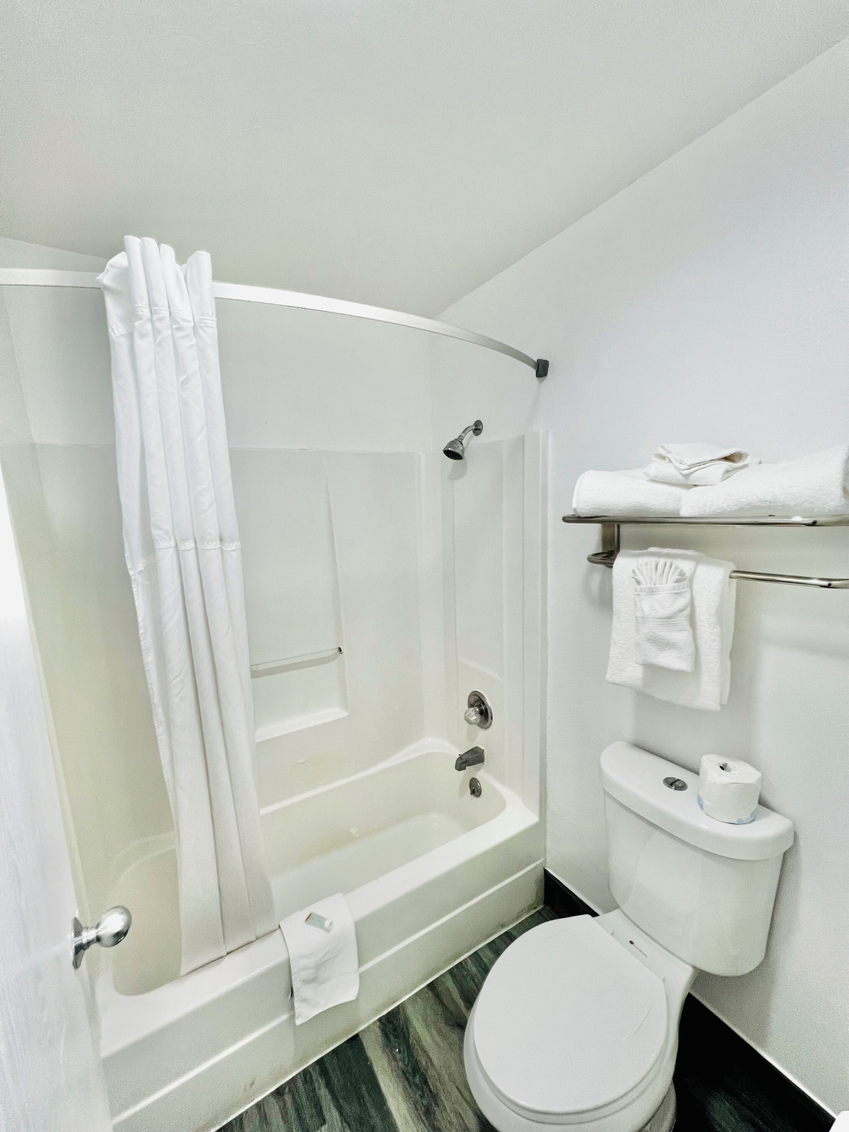 Un baño con bañera, inodoro y cortina de ducha.