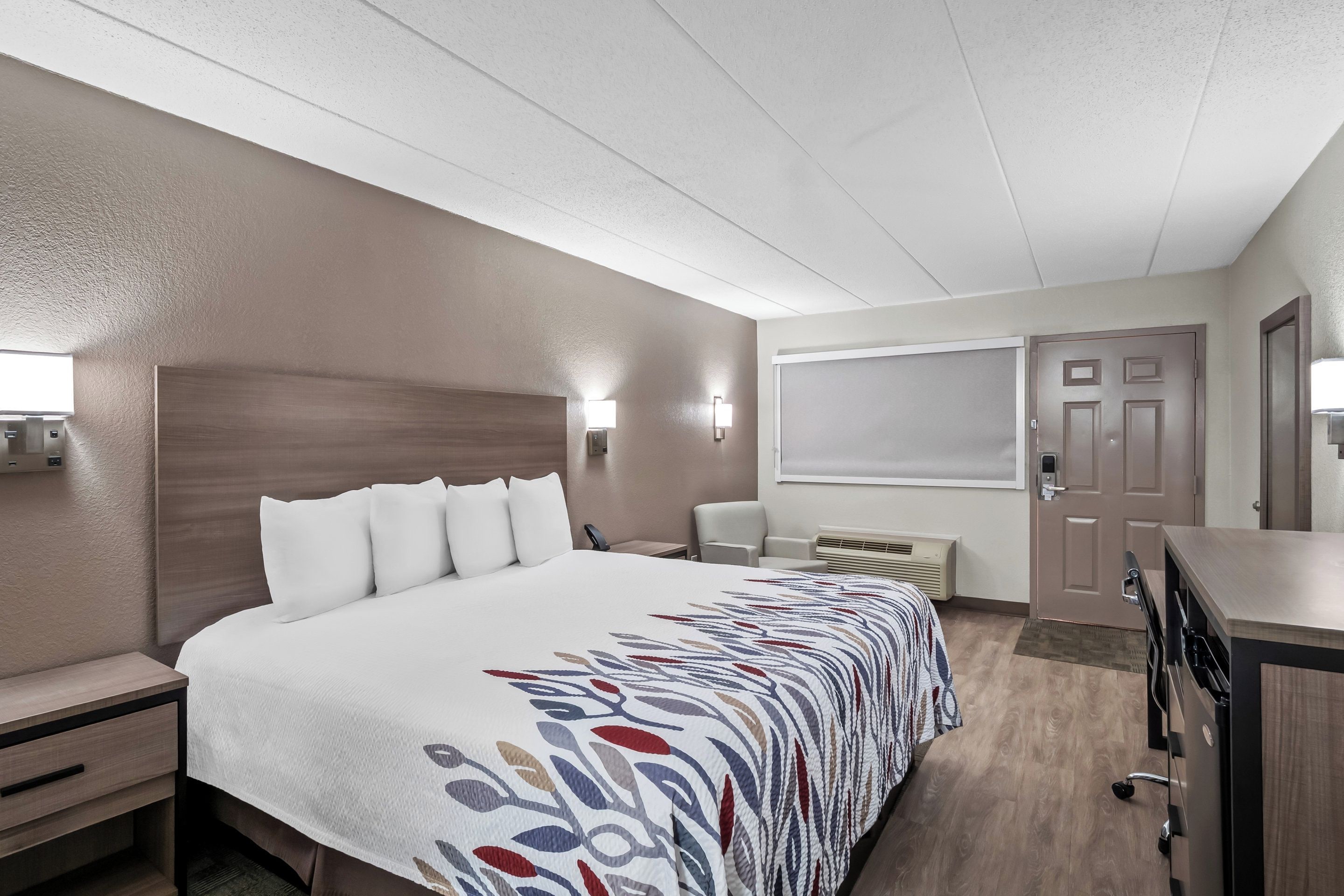 A hotel room with a large bed, bedside tables, a desk, and a wardrobe.