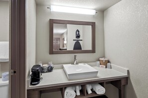 A bathroom with a white sink, a mirror, a coffee maker, and a towel rack. - Red Roof Inn Ann Arbor - U of Michigan South (Ann Arbor)
