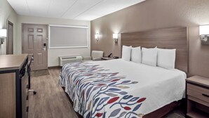 Habitación de hotel con una cama grande, un escritorio, una silla y un equipo de aire acondicionado instalado en la pared.