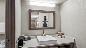 A bathroom with a white sink, a mirror, a coffee maker, and a towel rack. - Red Roof Inn Ann Arbor - U of Michigan South (Ann Arbor)