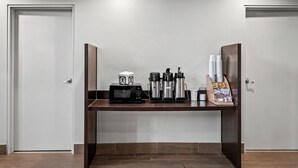 Una kitchenette equipada con microondas, cafetera y tazas de café.