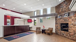 A reception area with a stone fireplace, a TV screen, and a reception desk. - Red Roof Inn Ann Arbor - U of Michigan South (Ann Arbor)