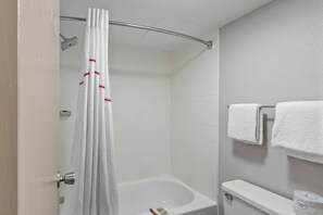 Un baño con cortina de ducha, bañera, inodoro y toallero con toallas.