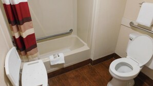 Baño con ducha, inodoro y una pequeña silla blanca.