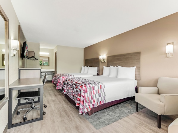 Una habitación de hotel con una cama grande, un escritorio, una silla y un televisor.