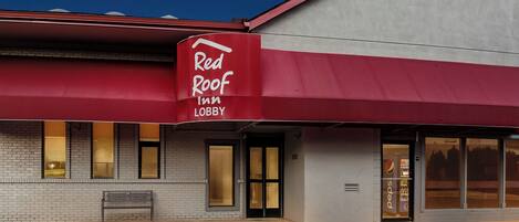 A Red Roof Inn with a brick facade, a red awning, and a Pepsi sign.