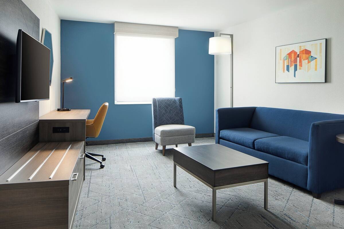 A modern room with a desk, a blue sofa, a small round table, and a chair.