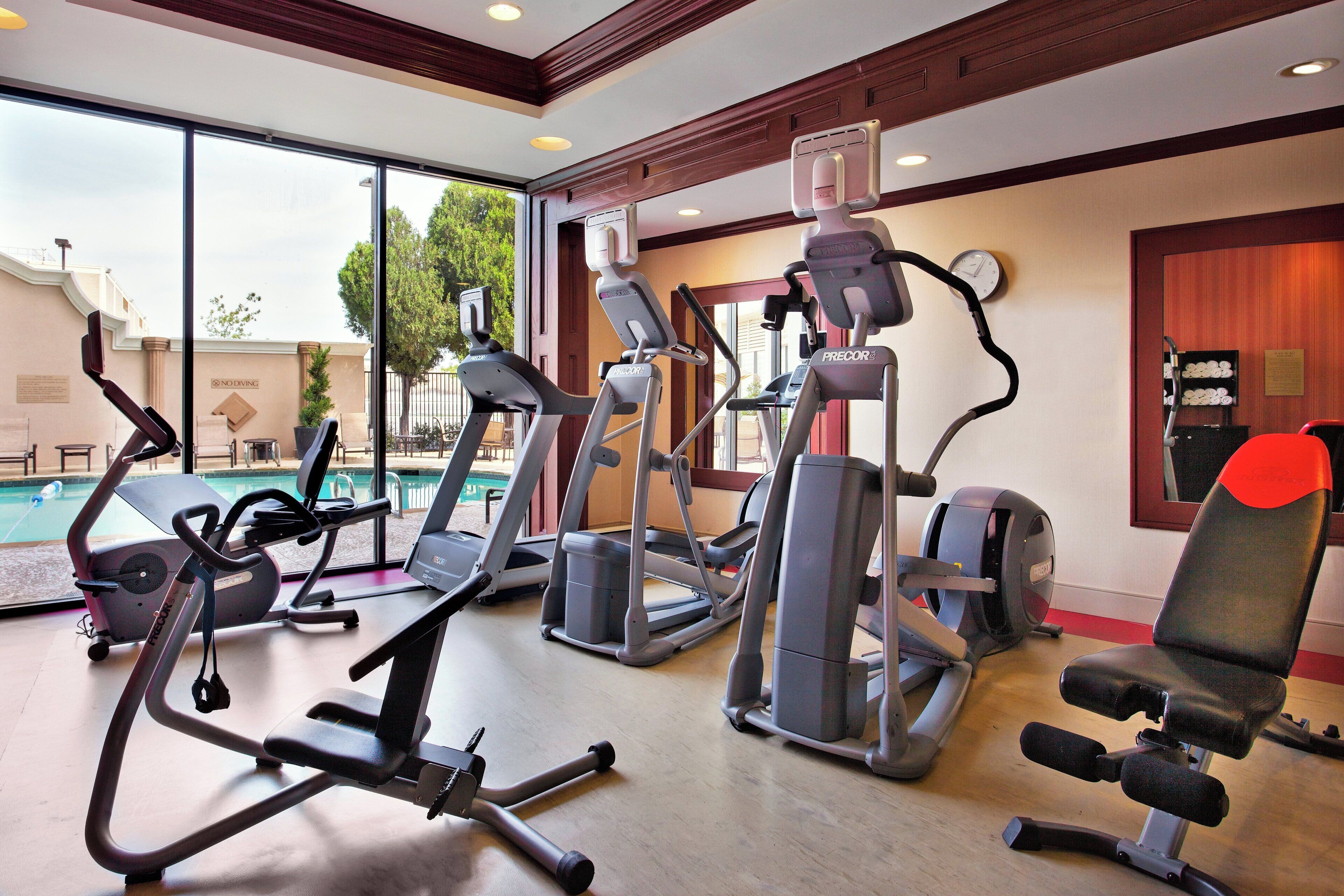 Un gimnasio con varios equipos de ejercicio, incluyendo cintas de correr, bicicletas estáticas y una máquina de remo.