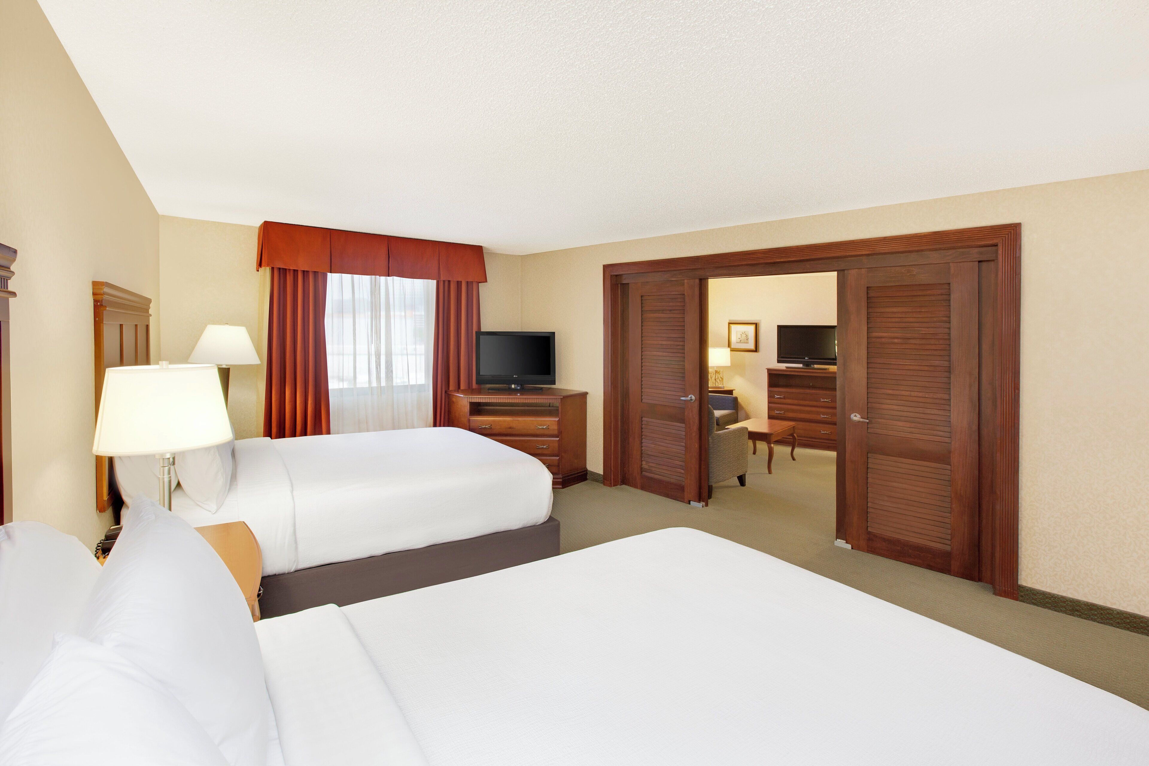 A hotel room with two beds, a desk, a television, and a wardrobe.
