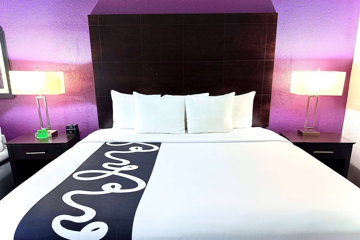 Een hotelkamer met een groot bed, twee nachtkastjes en een hoofdbord.