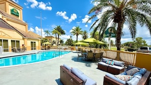 A pool area with a swimming pool, outdoor seating, and palm trees. - La Quinta Inn & Suites by Wyndham Orlando Universal area (Orlando)