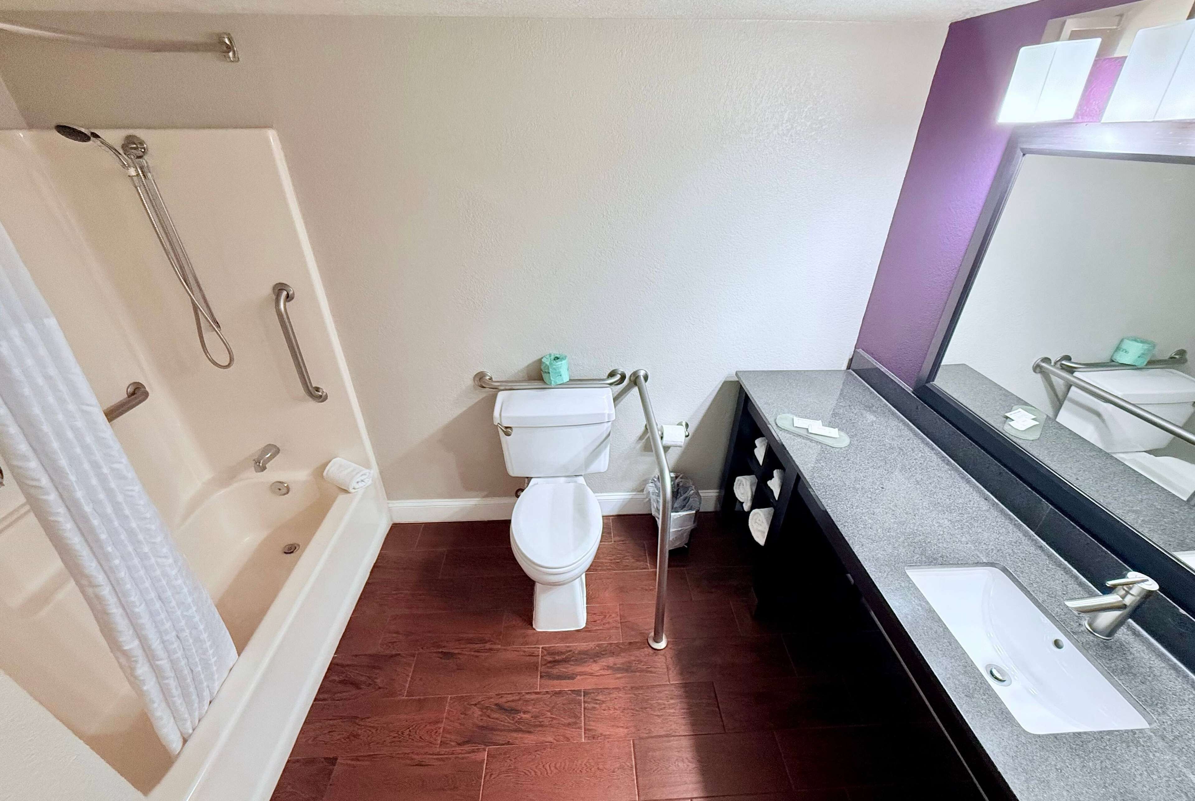 A bathroom with a bathtub, toilet, and a sink with a mirror.