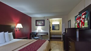 Een hotelkamer met een bed, een bureau, een stoel, een televisie en een spiegel.
