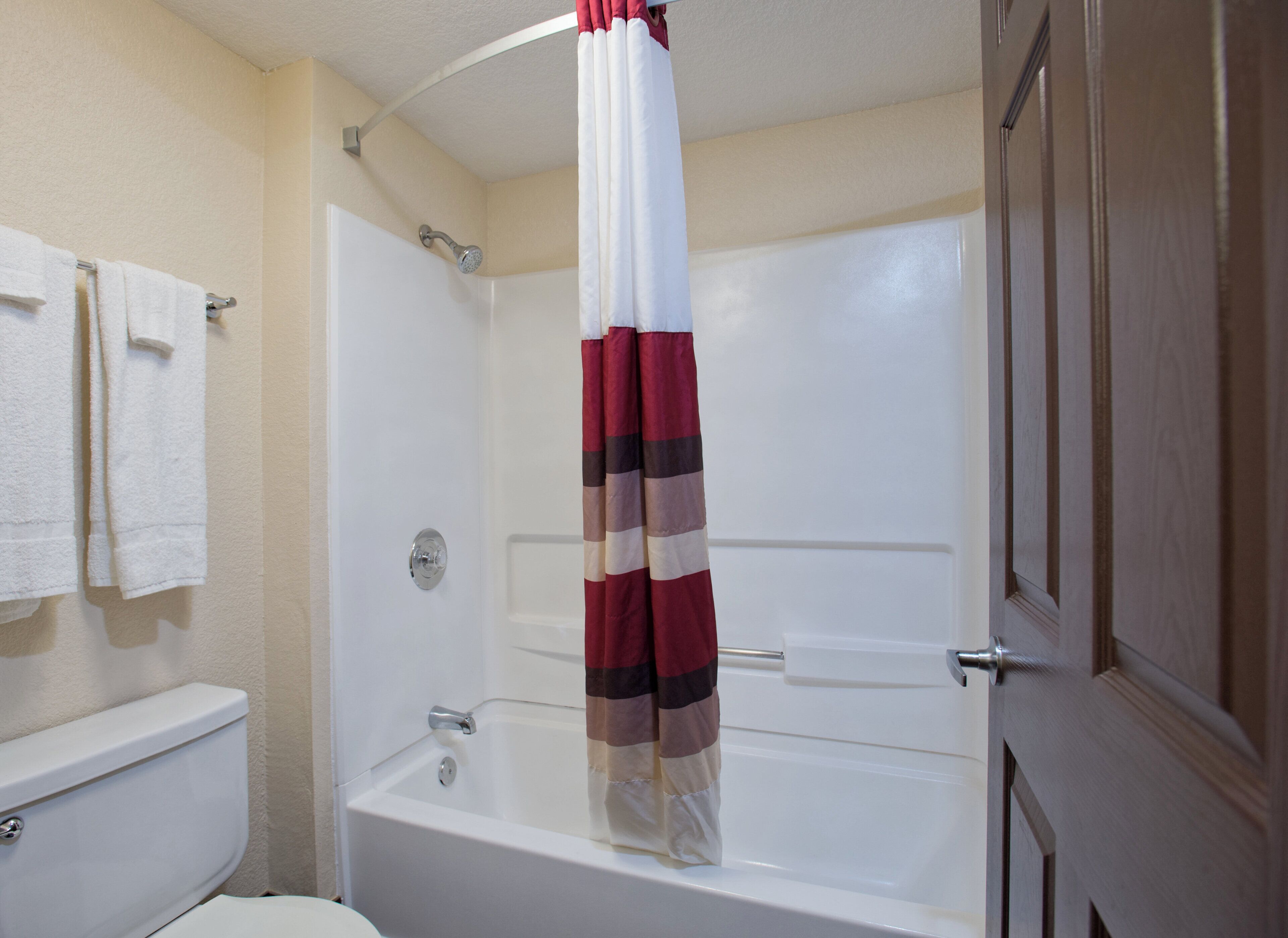 A bathroom with a white bathtub, a shower curtain, and a toilet.