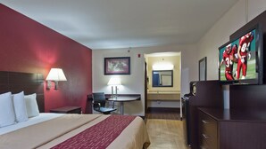 Een hotelkamer met een bed, een bureau, een stoel, een televisie en een badkamer zichtbaar door een geopende deur.