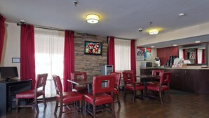 Een hotelkamer met een eethoek, een aan de muur bevestigde televisie en een keukenblad met een koffieapparaat.