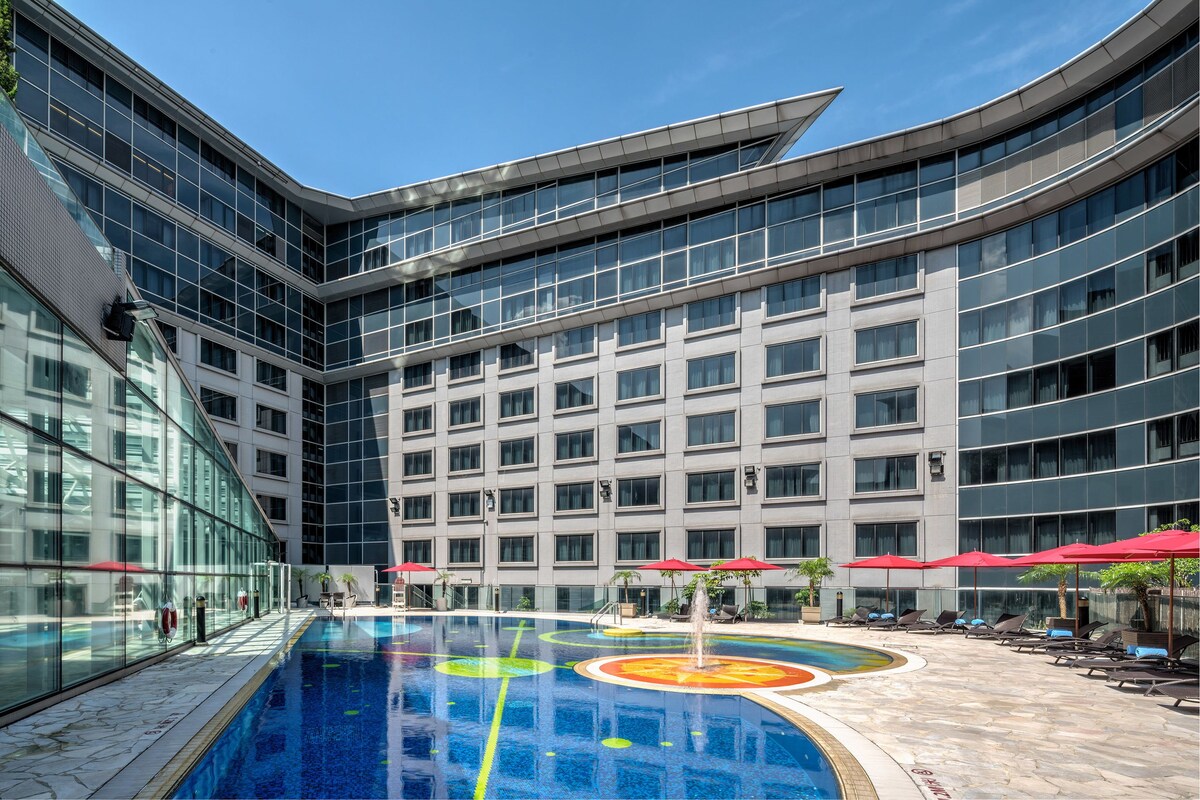 Una piscina techada, una piscina al aire libre, sombrillas