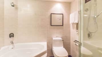 A modern bathroom with a bathtub, toilet, and glass-enclosed shower area.