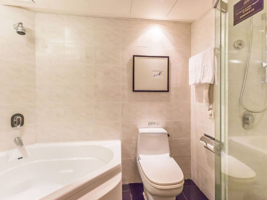 A modern bathroom with a bathtub, toilet, and glass-enclosed shower area.