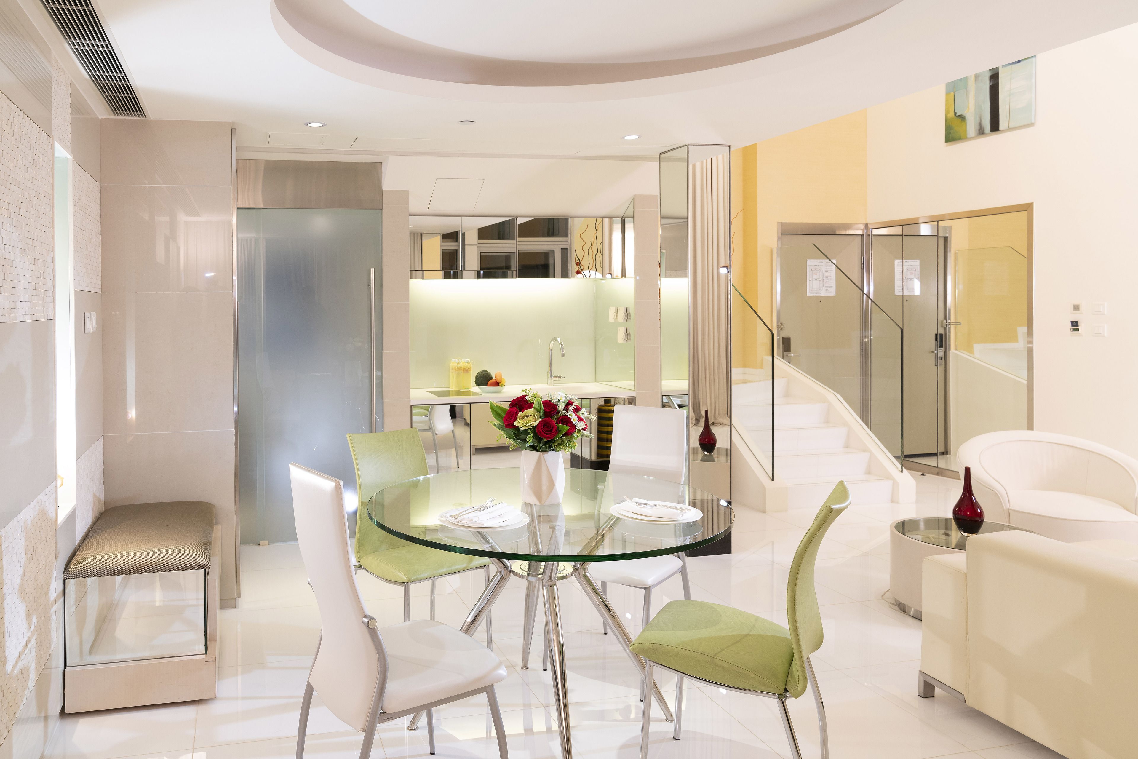 Un intérieur moderne avec une table à manger en verre, entourée de chaises, d’un canapé et d’un banc.