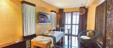 Habitación de hotel con cama, zona de estar con sillón, mesita pequeña y un panel decorativo en la pared.