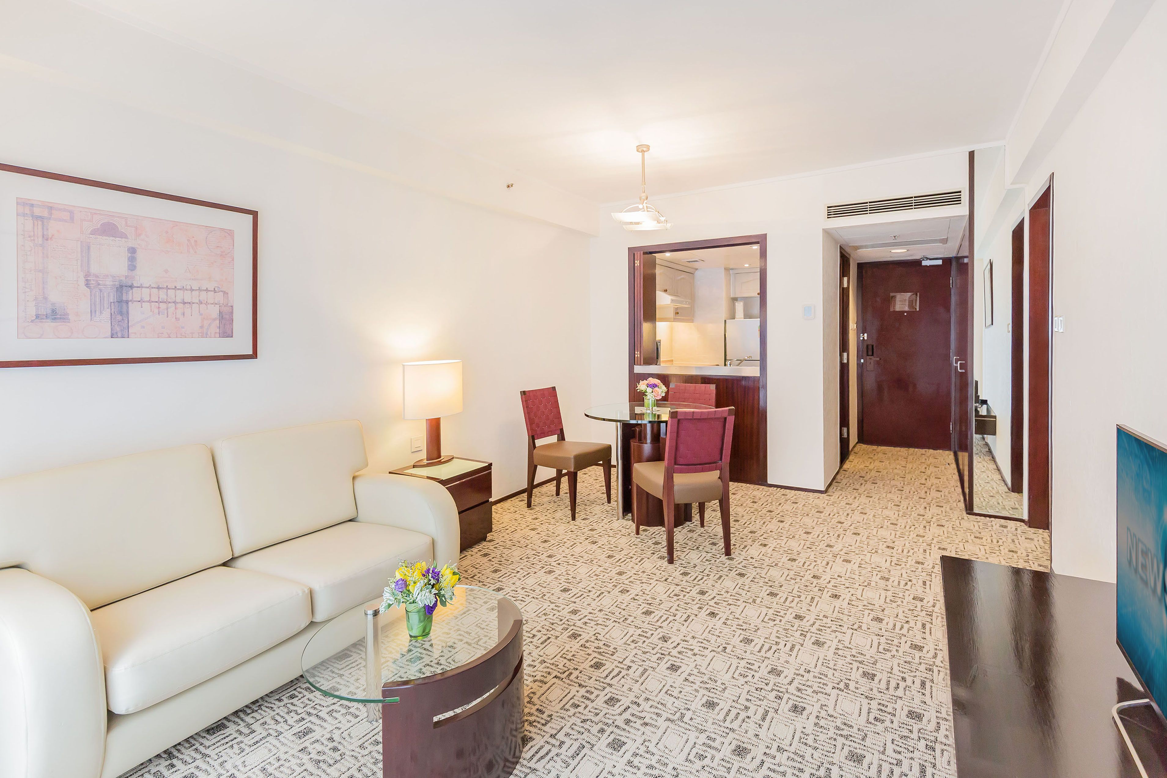Hotelkamer met een bank, een klein tafeltje met een bloemenvaas, een stoel, een bureau en een televisie.