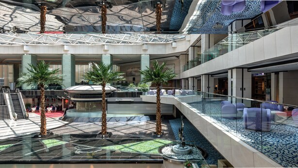 A multi-level atrium with a central water feature, palm trees, and seating areas. - Regal Airport Hotel (Chek Lap Kok)