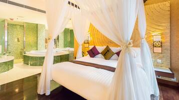 A spacious bedroom with a large bed, a sitting area, and a bathroom with a green mosaic wall.