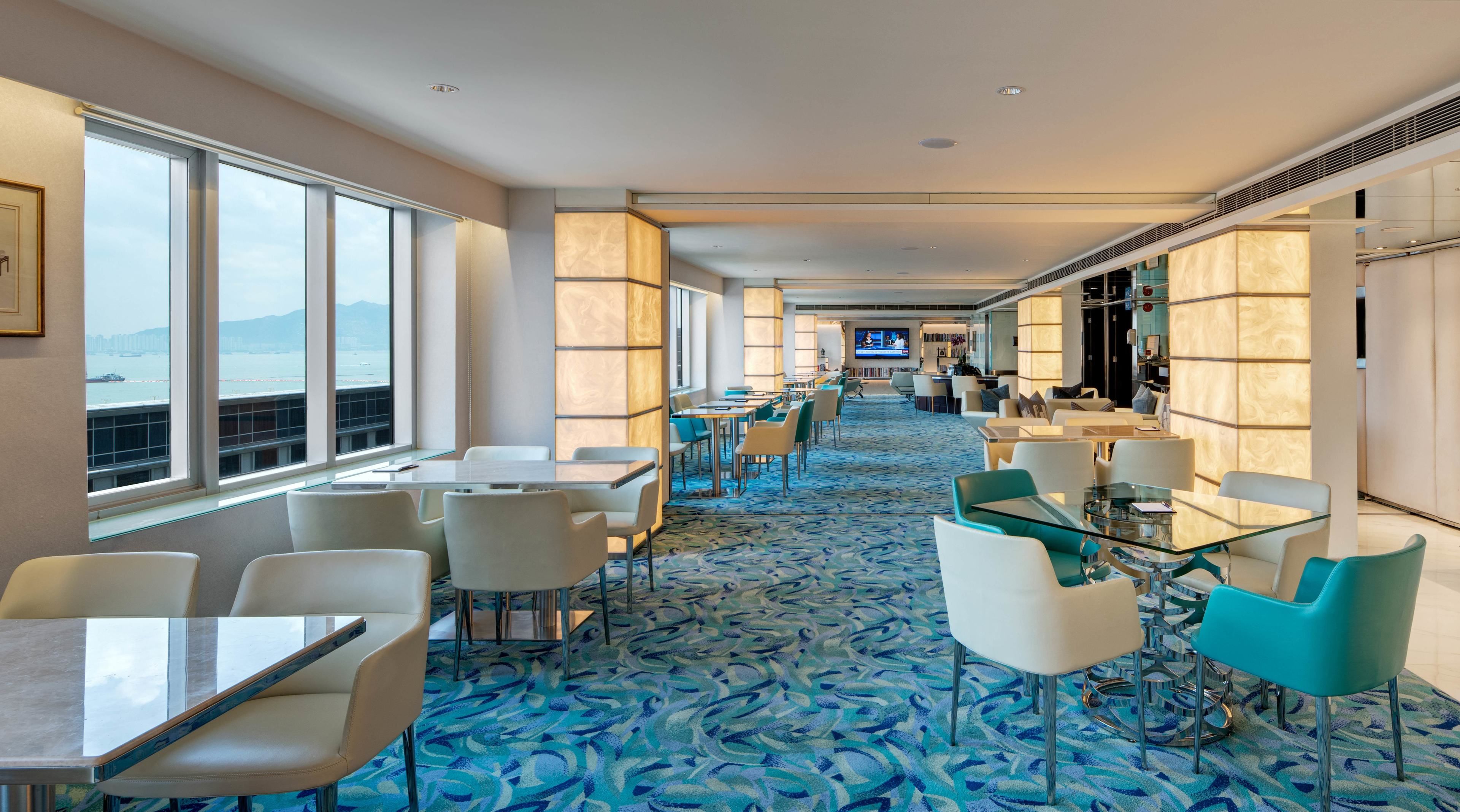 A hotel lobby with a long corridor, seating areas, and a view of the sea.