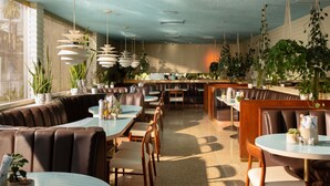 Um restaurante com cabines e mesas, com plantas penduradas e um espaço de bar.
