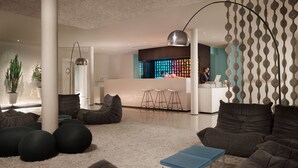 Uma área de estar moderna com balcão de recepção, assentos e uma parede decorativa.