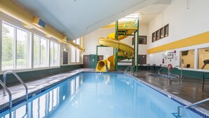 An indoor swimming pool with a yellow slide, large windows, and a high ceiling. - Mountain Retreat Hotel (Squamish)