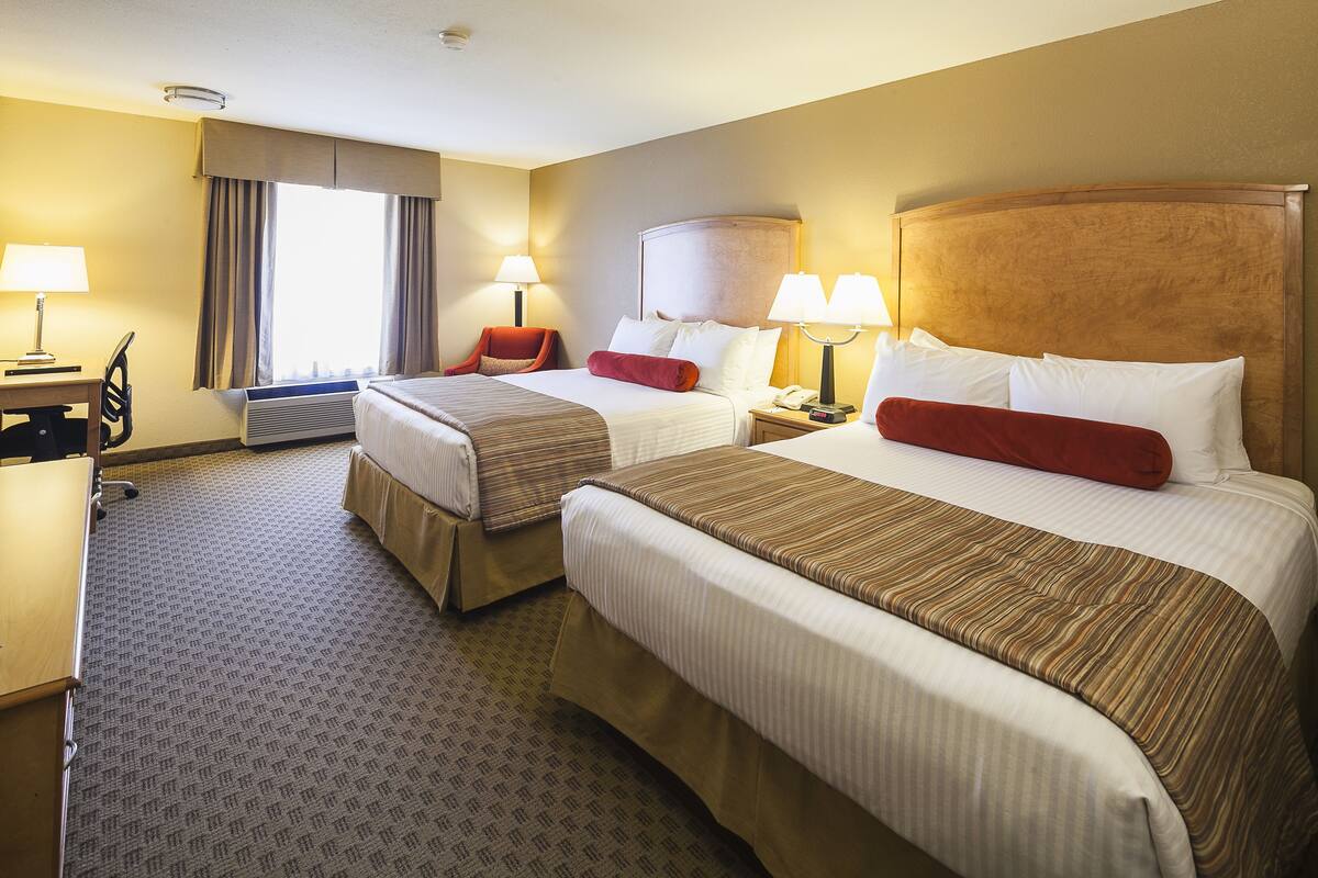 Ein Hotelzimmer mit zwei Betten, einem Schreibtisch und einem Stuhl.
