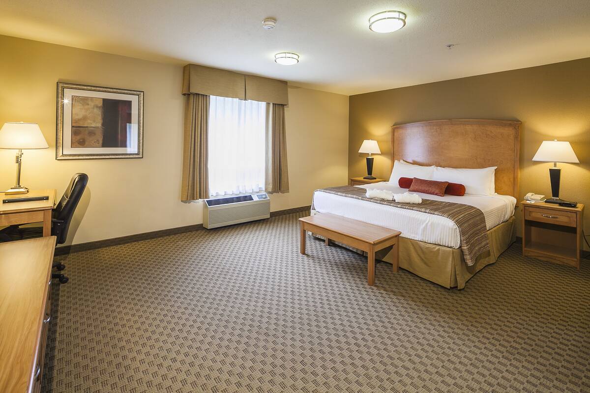 Ein Hotelzimmer mit einem großen Bett, Nachttischlampen, einem Schreibtisch und einem Sessel.