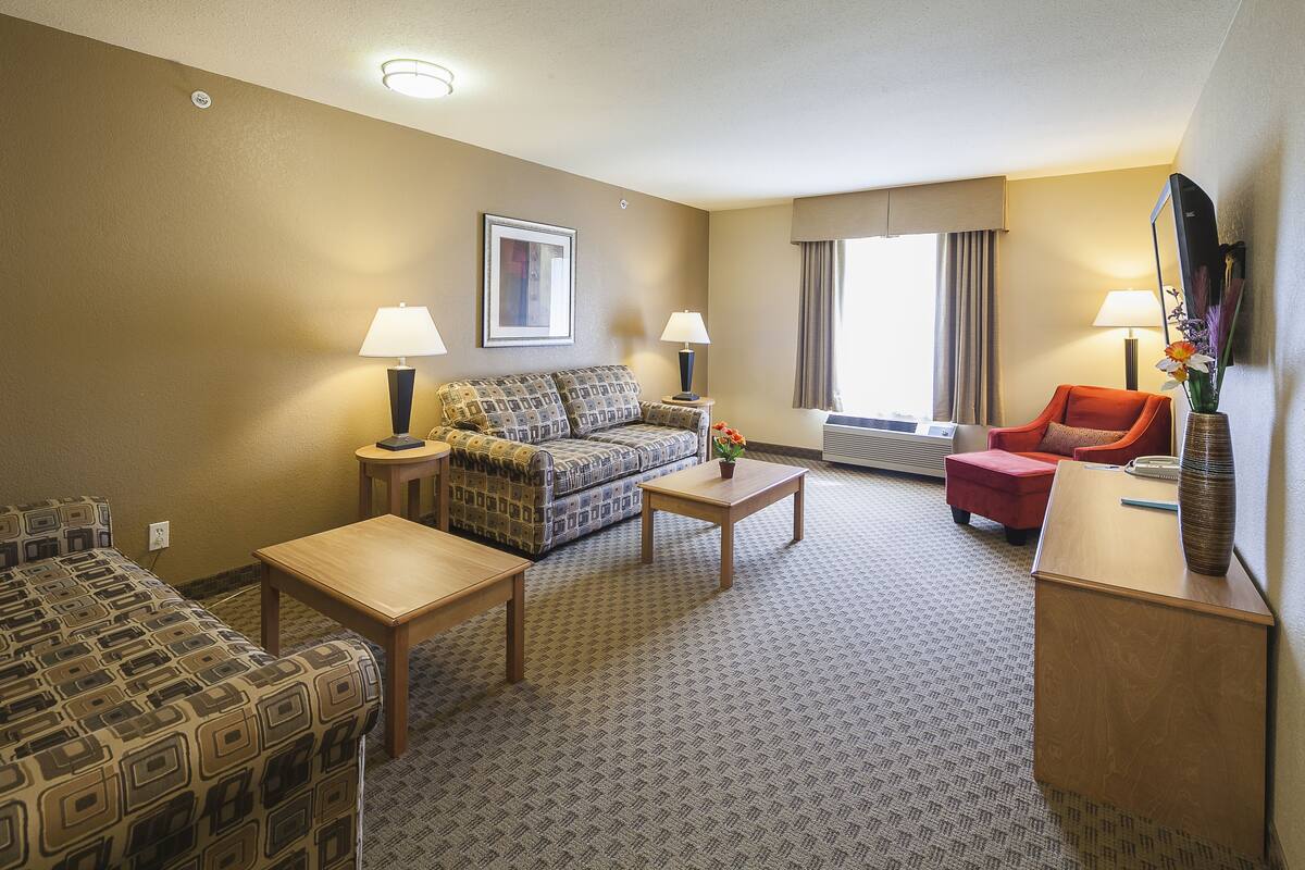 Ein Hotelzimmer mit einer Couch, zwei Sesseln, einem Couchtisch und einem Fernseher.