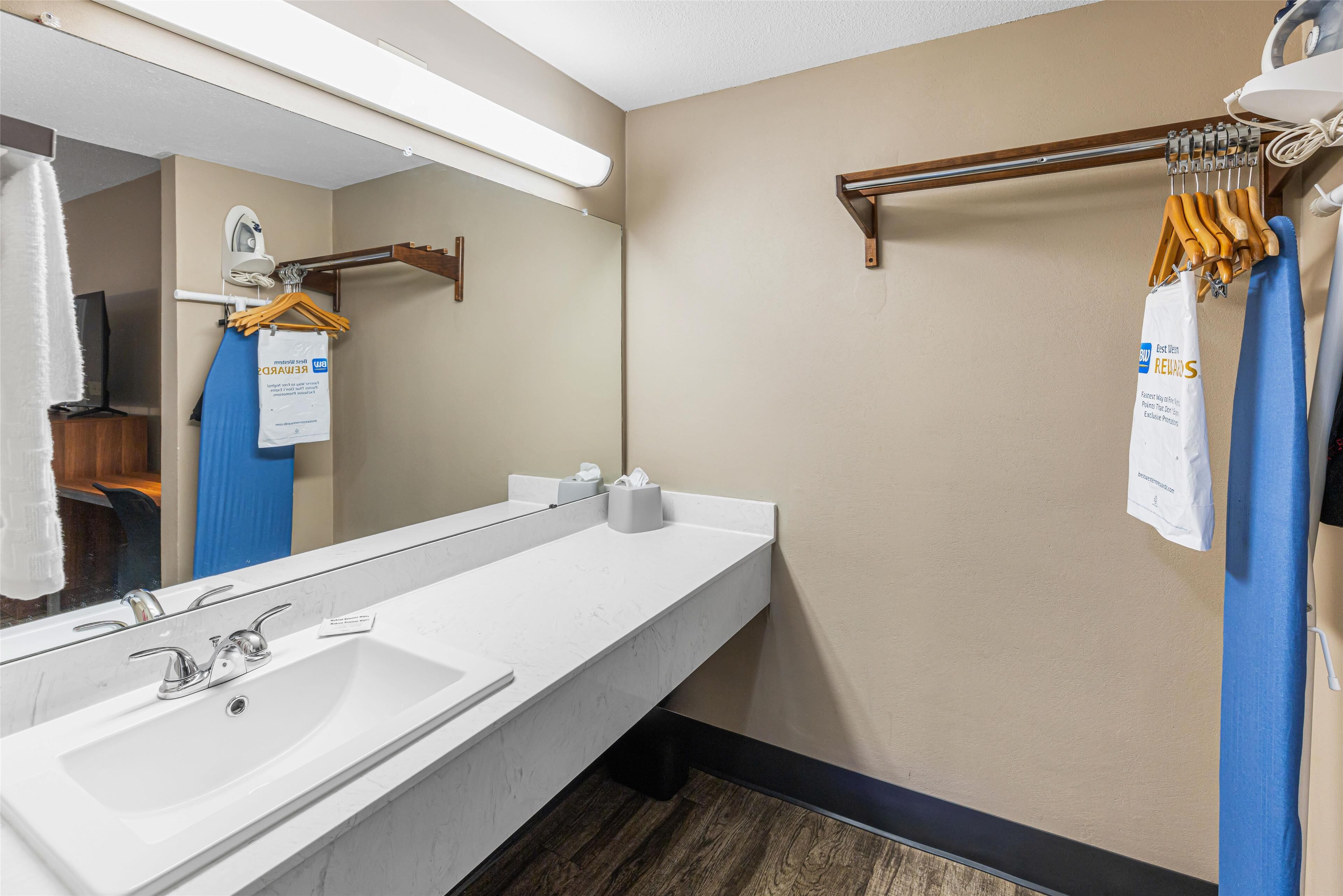 Un baño de hotel con un espejo grande, un lavabo blanco y un perchero para toallas.