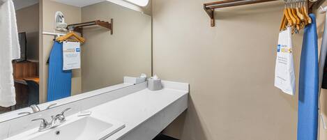 Un baño de hotel con un espejo grande, un lavabo blanco y un perchero para toallas.