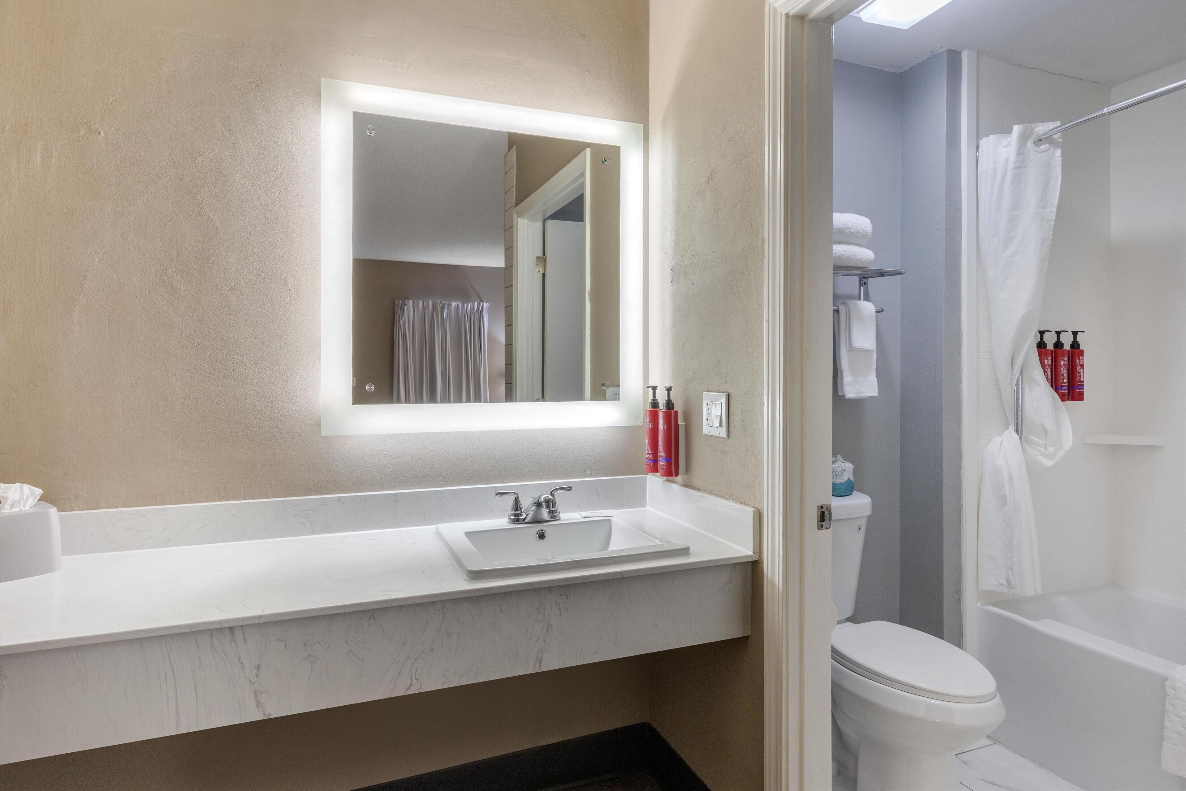 Een badkamer met een wit wastafelmeubel, spiegel en toilet.