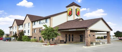 A hotel with a parking lot, a covered entrance, and a sign indicating a clearance of 9'6'.