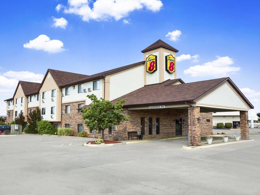 A hotel with a parking lot, a covered entrance, and a sign indicating a clearance of 9'6'.