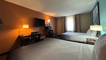 A hotel room with two beds, a desk with a chair, a television, and a window with curtains.