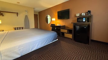 Habitación de hotel con cama, escritorio, televisor de pantalla plana, microondas y refrigerador pequeño.