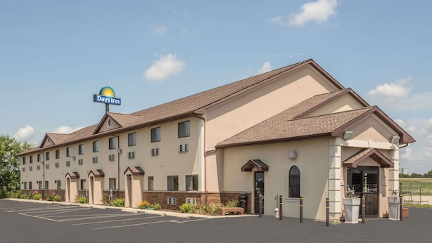 A Bays Inn with a parking lot and a large building with multiple windows and a sign. - Days Inn by Wyndham Le Roy/Bloomington Southeast (Le Roy)