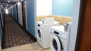 A hotel hallway with a checkered floor, two washing machines, and a wooden accent wall. - Days Inn by Wyndham Le Roy/Bloomington Southeast (Le Roy)
