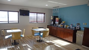 A dining area with a kitchen counter, wooden flooring, and a television mounted on the wall. - Days Inn by Wyndham Le Roy/Bloomington Southeast (Le Roy)
